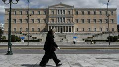 A woman wearing a face mask walks past the empty Syntagma Square in Athens, in front of the Greek Parliament early during the outbreak of COVID-91.