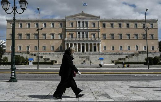A woman wearing a face mask walks past the empty Syntagma Square in Athens, in front of the Greek Parliament early during the outbreak of COVID-91.