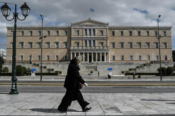 A woman wearing a face mask walks past the empty Syntagma Square in Athens, in front of the Greek Parliament early during the outbreak of COVID-91.