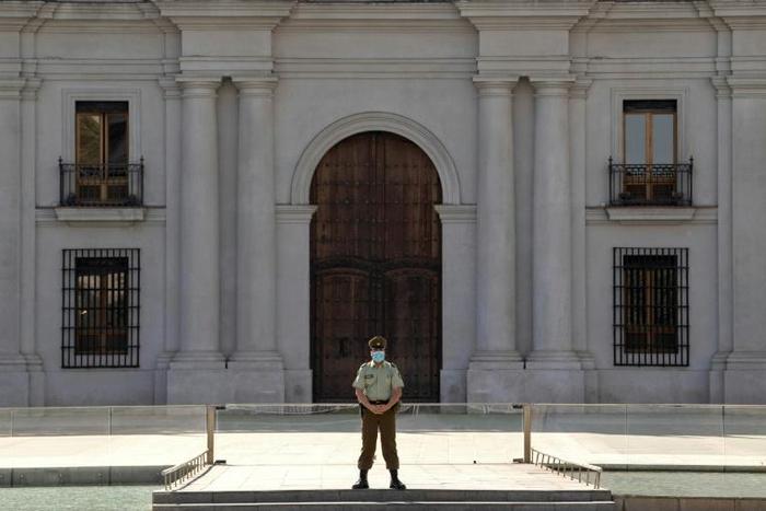 A police officer wears gloves and a face mask as he stands guard outside La Moneda presidential palace in Santiago, Chile, on April 09, 2020