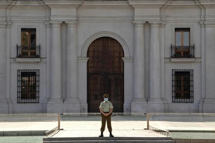 A police officer wears gloves and a face mask as he stands guard outside La Moneda presidential palace in Santiago, Chile, on April 09, 2020