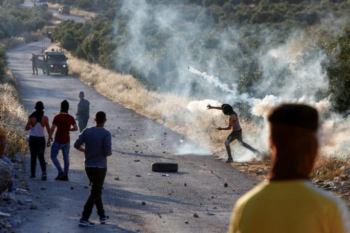 A Palestinian demonstrator returns a tear gas canister during clashes with Israeli soldiers in the town of Tuqua in the Israeli-occupied West Bank on May 28