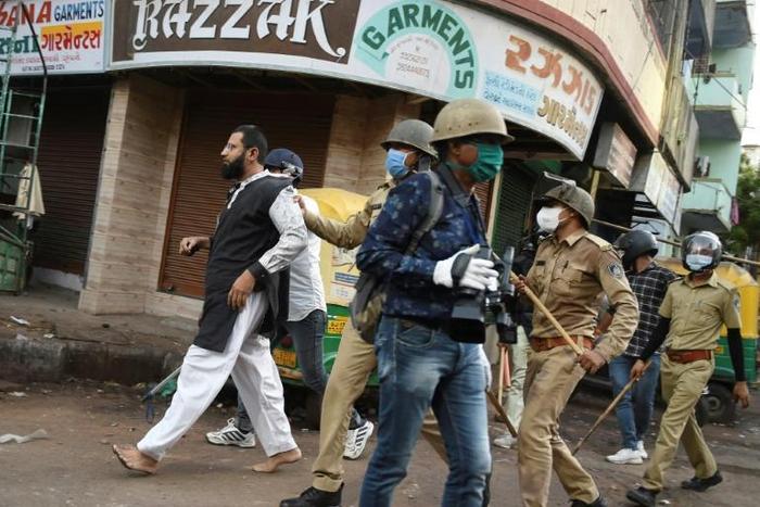 Gujarat police detain a man after he threw stones at them during a government-imposed nationwide lockdown in Ahmedabad on Friday