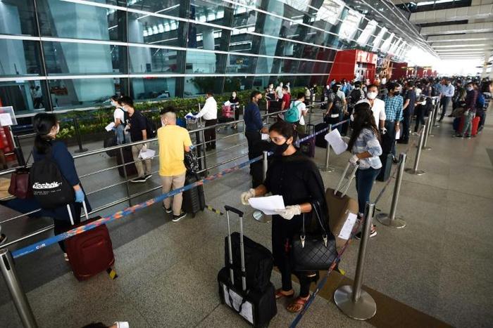At New Delhi airport, hundreds of people anxious to get home but apprehensive about the risks queued from before dawn