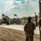 US soldiers stand along a road across from Russian military armored personnel carriers near the village of Tannuriyah in Syria's northeastern Hasakah province on May 2, 2020