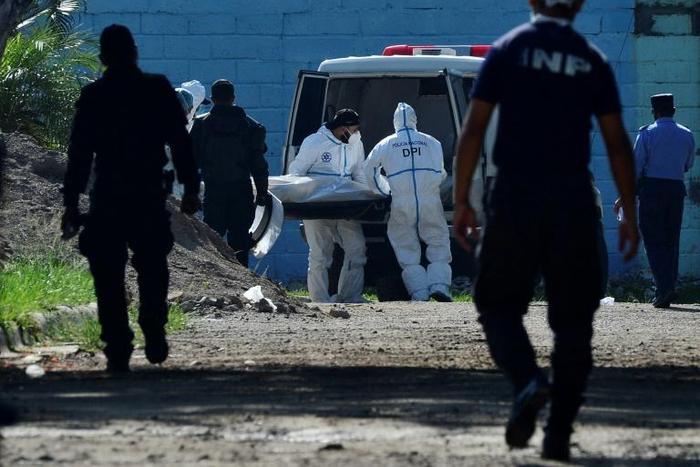 Forensic experts take away a corpse from the women's prison in Tamara, Honduras following the murder of six inmates