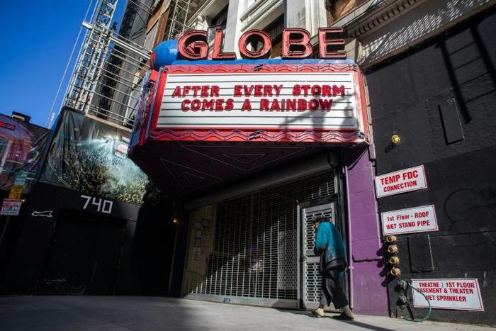 A homeless man walks by a closed theater in Los Angeles, on March 21, 2020, as California  grapples with its part of the global coronavirus pandemic