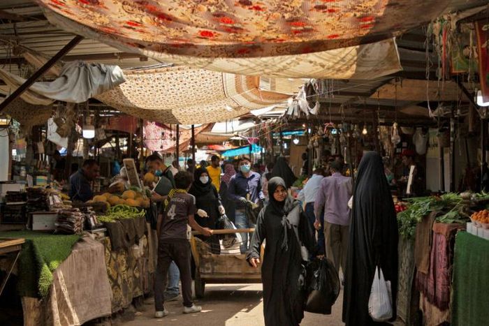 Iraqis walk through a fresh produce market in the southern Iraqi city of Basra as some lockdown restrictions imposed during the novel coronavirus pandemic have been eased