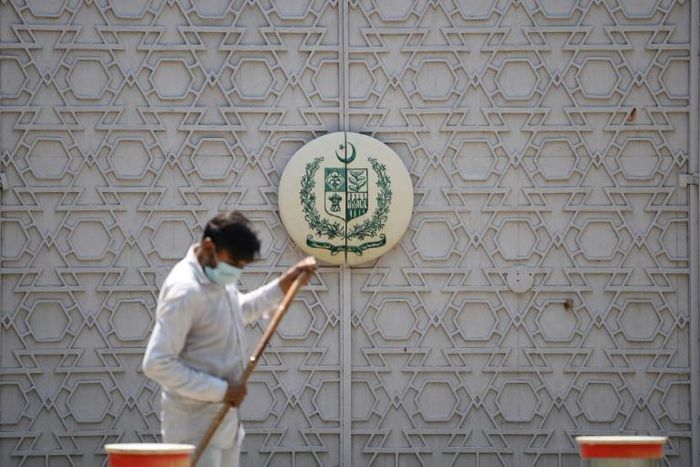 A man sweeps in front of the main gate of the Pakistan High Commission in New Delhi