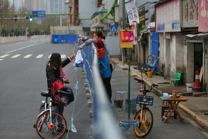 Barriers to stop the spread of the coronavirus in Wuhan have divided communities