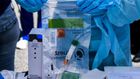 A health worker stores coronavirus test samples at a drive-through clinic in West Palm Beach, Florida