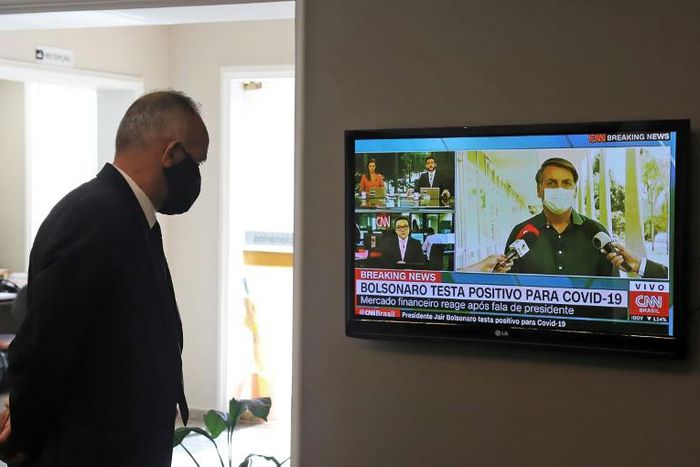 A funeral home worker in Curitiba watches the live news as President Jair Bolsonaro announces his positive COVID-19 test result