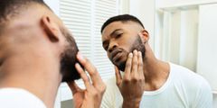 Man checks his beard in the mirror
