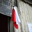 A woman hangs colored flags on the door of her house to signal she needs to be delivered food (white) and medicine (red) for her sick husband, at La Brigada neighbourhood in Guatemala City