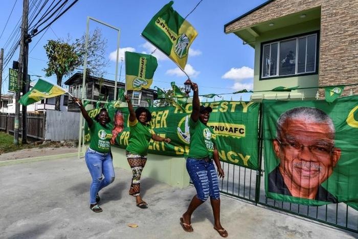 Supporters of presidential candidate David Granger cheer and wave flags in front of their house in Georgetown, Guyana, on March 1, 2020