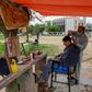 A barber wearing a facemask cuts a customer's hair at an open-air stall in Islamabad