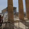 A worker (pictured May 18, 2020) wearing a protective mask cleans a divider made of plexiglass at the entrance of the Acropolis in Athens amid the pandemic of the novel coronavirus