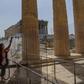 A worker (pictured May 18, 2020) wearing a protective mask cleans a divider made of plexiglass at the entrance of the Acropolis in Athens amid the pandemic of the novel coronavirus