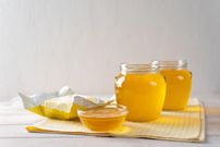 Hot homemade ghee butter in glass jars on a light background.