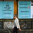 A pedestrian walks past public service announcement posters, negating a conspiracy that 5G telecommunications technology causes the coronavirus, in  Melbourne
