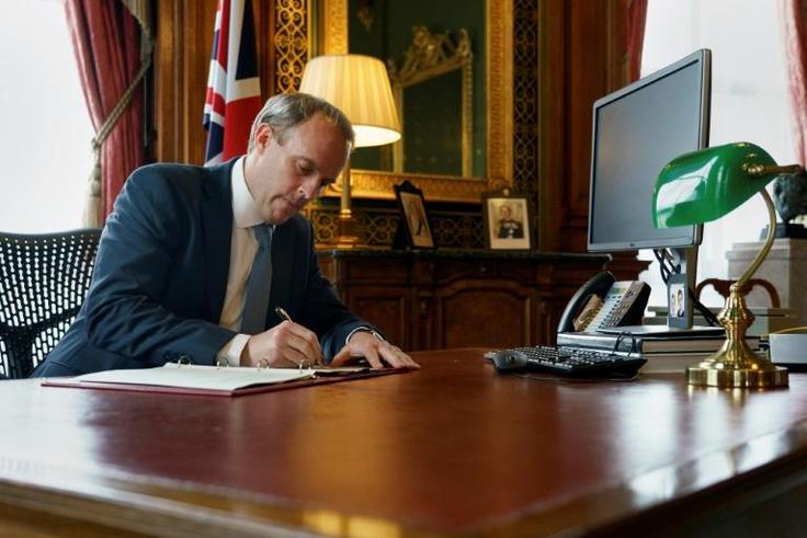 A handout image released by 10 Downing Street, shows Britain's Foreign Secretary Dominic Raab signing a letter to fellow MPs, in the Foreign & Commonwealth Office in central London on July 6, 2020, following the launch of new Human Rights Sanctions