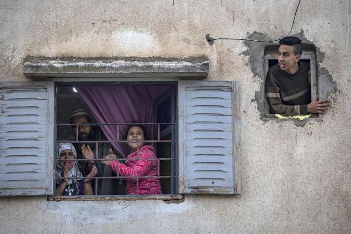 Moroccans confined at home thank the authorities from their windows as security forces and health workers instruct people to return to and remain at home as a measure against the COVID-19 coronavirus pandemic, in Rabat's district of Takadoum