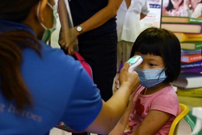 A young pupil has her temperature checked on the first day schools resumed in Singapore following the easing of some coronavirus restrictions