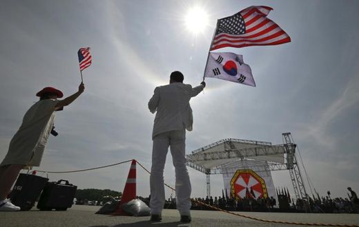 A man and a woman wave flags during a ceremony at the US Camp Humphreys in Pyeongtaek in June, 2019
