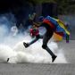 A protester kicks back a tear gas canister fired by security forces on opposition marchers in Caracas