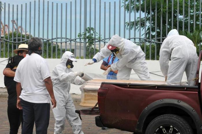 Workers wrap with plastic a coffin with the remains of a person who died from the coronavirus, COVID-19 in Guayaquil, Ecuador
