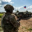 US soldiers stand along the side of a road across near a Russian military armoured personnel carrier (APC), near the village of Tannuriyah in the countryside east of Qamishli in Syria's northeastern Hasakah province on May 2, 2020
