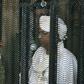 Sudan's deposed president Omar al-Bashir stands in a defendant's cage during the opening of his corruption trial in Khartoum last August