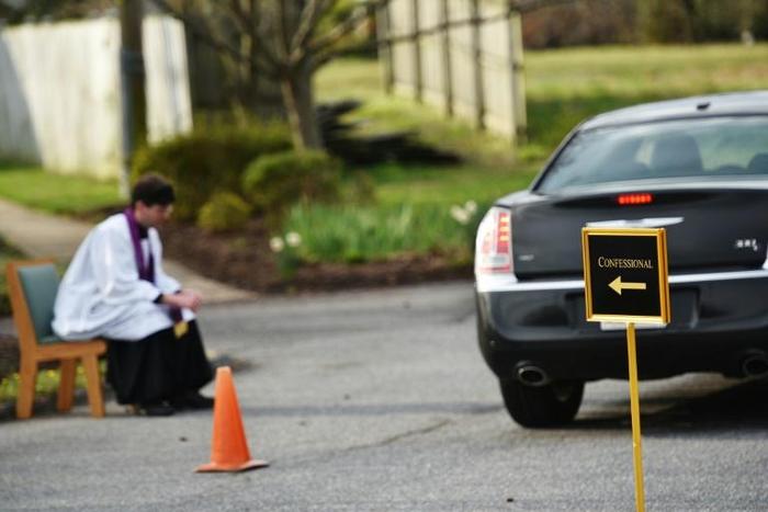 Father Scott Holmer is careful to keep a safe distance from his flock and asks parishioners to stay in their vehicles