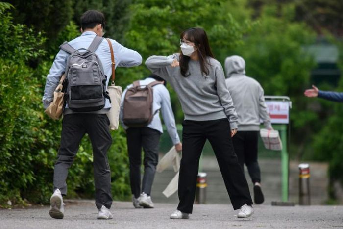 A staff member greeted students with an elbow bump as they returned to Kyungbock High School in Seoul after being closed for more than two-months because of coronavirus
