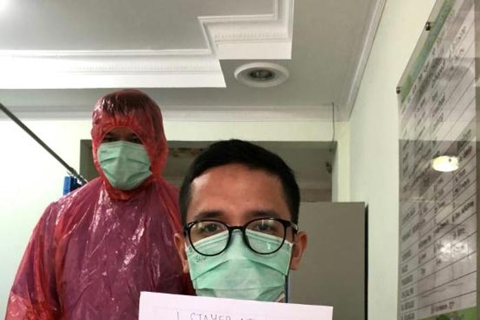 Doctor Muhammad Farras Hadyan, wearing a raincoat because of a shortage of proper protection gear, poses for a selfie during a break from treating patients with coronavirus, in Jakarta