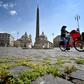 Grass grows between cobblestones as a woman rides a bicycle across Piazza del Popolo on April 24, 2020 in Rome, during the country's lockdown aimed at stopping the spread of the COVID-19 pandemic, caused by the novel coronavirus