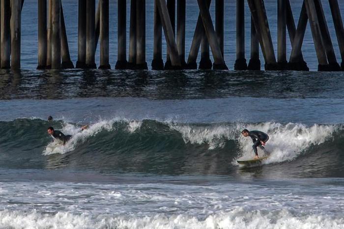 Surfers catch a wave in Huntington Beach, California on May 2