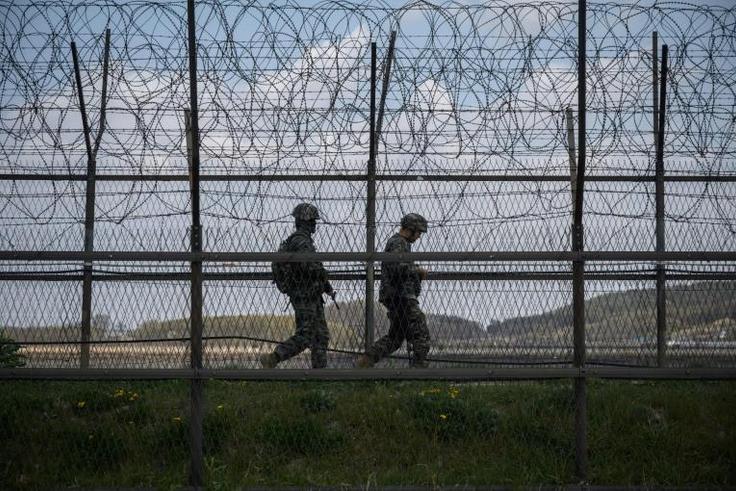 South Korean soldiers patrolling along a barbed wire fence at the  Demilitarized Zone with North Korea