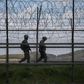 South Korean soldiers patrolling along a barbed wire fence at the  Demilitarized Zone with North Korea