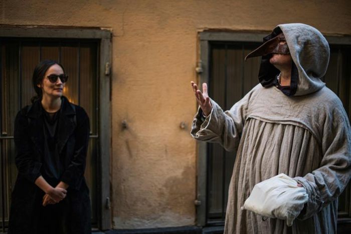 Tour guide Mike Anderson (R) takes visitors on a "plague walk" in Stockholm's Old Town in May 2020