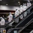 Medical staff wearing protective suits ride down an escalator at Moscow's Sheremetyevo airport