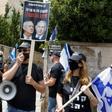 An Israeli protester holds a placard with a picture of Prime Minister Benjamin Netanyahu and his former rival Benny Gantz in Jerusalem