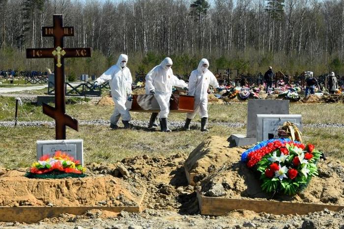 Cemetery workers in protective gear bury a coronavirus victim at a cemetery on the outskirts of Saint Petersburg. Russia has reported a remarkably low death toll but critics have cast doubt on the numbers