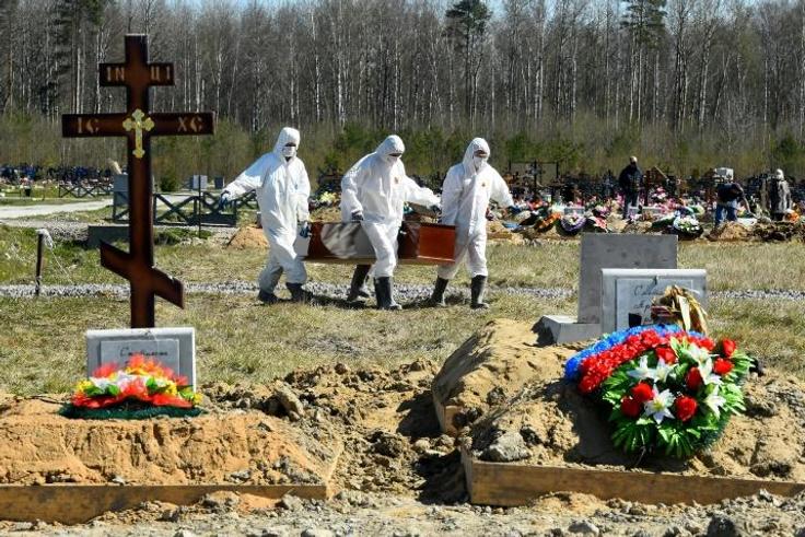 Cemetery workers in protective gear bury a coronavirus victim at a cemetery on the outskirts of Saint Petersburg. Russia has reported a remarkably low death toll but critics have cast doubt on the numbers