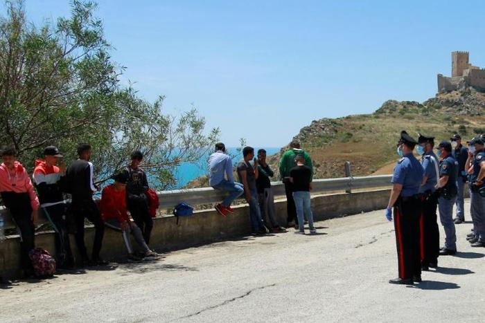 Police are shown checking and detaining some of the migrants, who left the beach in small groups
