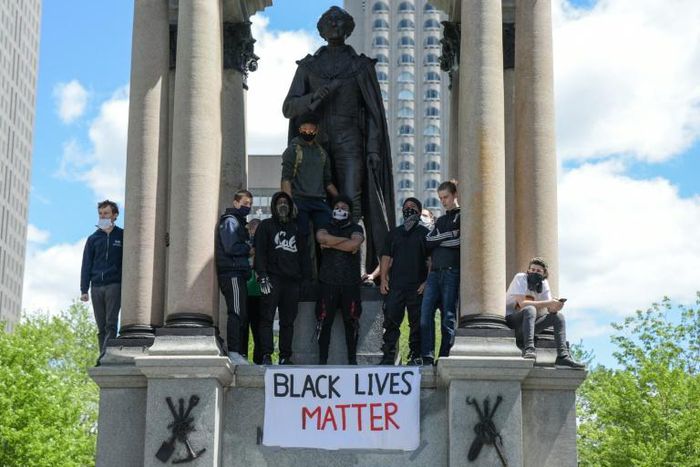 Protesters climb a statue of John A. Macdonald, Canada's first prime minister, during a march against police brutality and racism in Montreal on June 7. Thousands have signed a petition to have the statue removed.