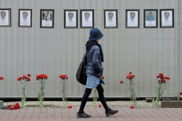 A woman walks past a makeshift memorial for Russian medical workers who have died from the COVID-19 disease, set up outside the local health department in Saint Petersburg. More than 70 have died so far.