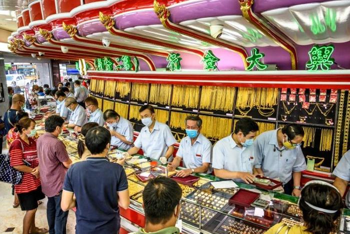 Customers in facemasks selling gold at a shop in Bangkok's Chinatown