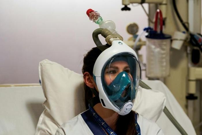 A medical worker tests a Decathlon snorkeling mask, with a 3D-printed respiratory valve fitting attached, at the Erasme Hospital in Brussels