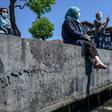 People over 65 wearing protective face masks sit and enjoy the sun on the Bosphorus in their first trip outdoors since a tough coronavirus lockdown was imposed nearly two months ago